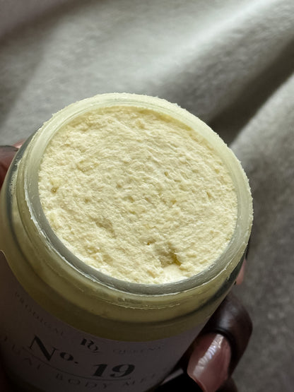 Jar of cream held by a hand with a blurred background